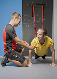 Personal trainer helping client with suspension training in gym