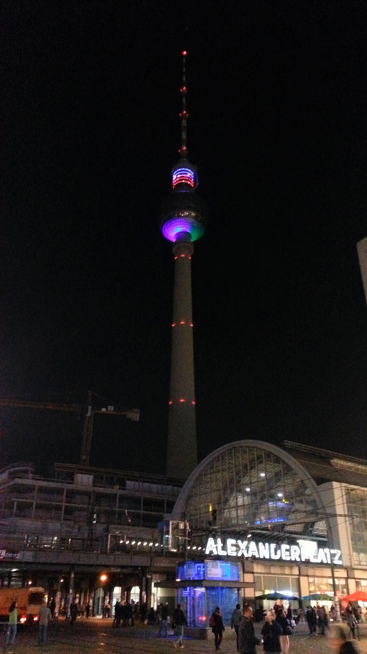 PEOPLE AT ILLUMINATED CITY AGAINST CLEAR SKY