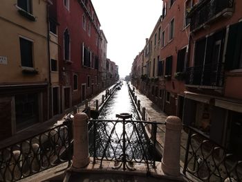 Canal amidst buildings against clear sky