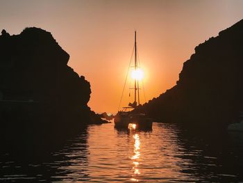 Silhouette sailboats in sea against sky during sunset