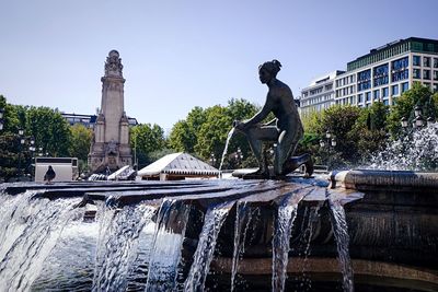 Fountain in city against clear sky