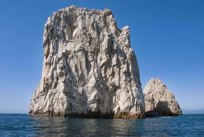 View of rock formation in sea against clear sky