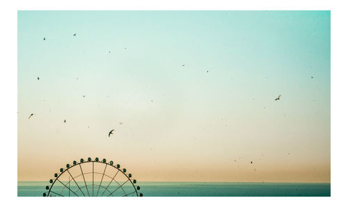 Ferris wheel in sea against clear sky