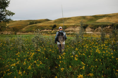 Man walking through tall grass to fish