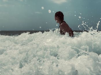 Rear view of boy enjoying in sea