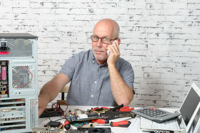 Portrait of businessman using mobile phone at desk in office