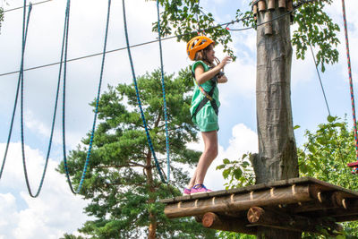 Adventure climbing high wire park - people on course in mountain helmet and safety equipment