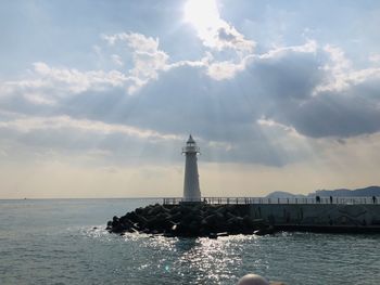 Lighthouse by sea against sky