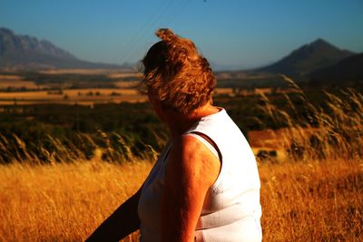 Woman sitting on field against sky during sunset