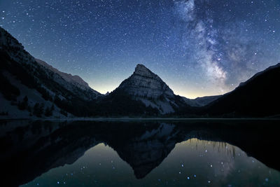 Scenic view of lake and mountains against sky at night