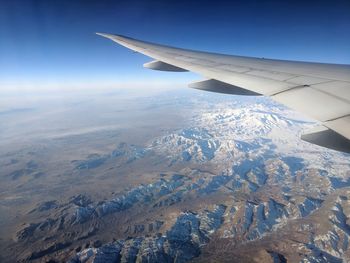 Aerial view of aircraft wing over landscape against sky