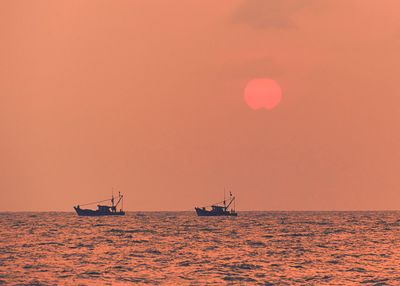 Boats sailing on sea against sky during sunset