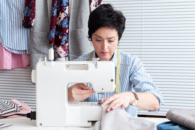 Craftswoman sewing textile on machine at workshop