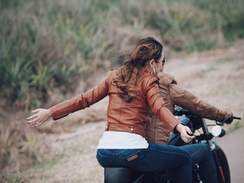 Rear view of couple riding motorcycle on road
