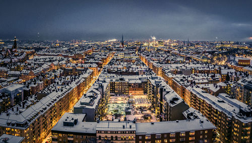 Aerial view of illuminated buildings in city against sky at night