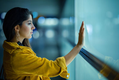 Young woman touching glass