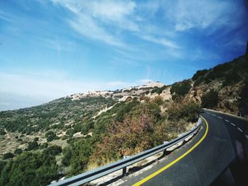 Road by mountain against sky