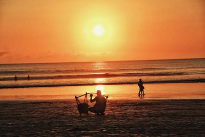 Silhouette people on beach against sky during sunset