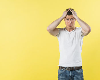 Portrait of young man standing against yellow wall