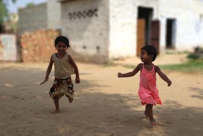 Full length of siblings running on sand