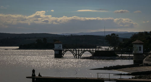 Bridge over river by buildings against sky