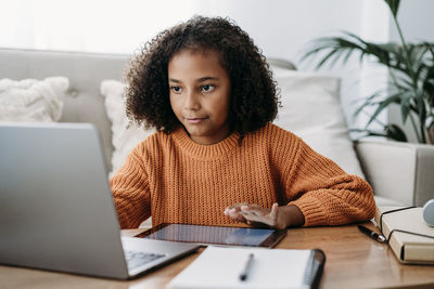 Girl doing homework on laptop and tablet pc at home