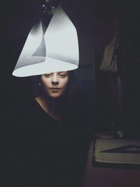 Portrait of young woman against black background