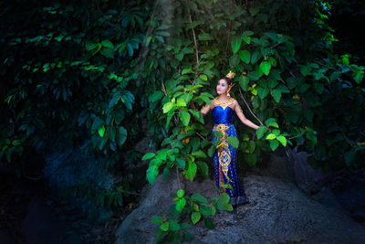 Woman standing amidst plants in forest