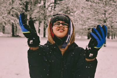 Portrait of smiling young woman standing in snow