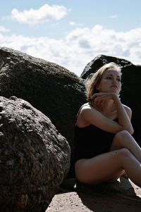 Woman sitting at beach against sky