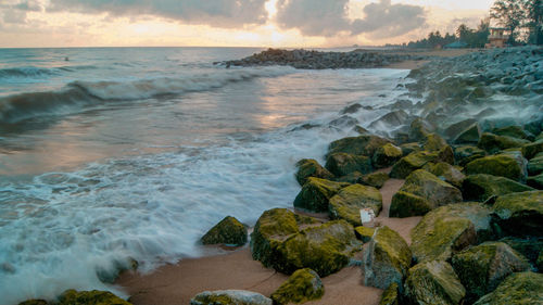 Rocks at beach against sky during sunset