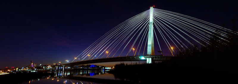 Illuminated bridge over river at night
