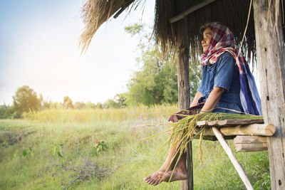 Senior woman sitting in shed at farm