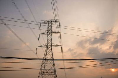 Low angle view of electricity pylon against sky during sunset