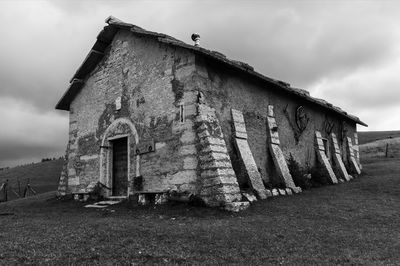 Abandoned building on field against sky