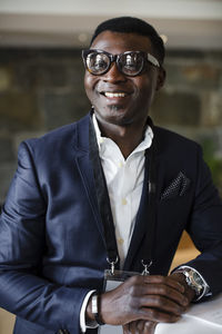 Portrait of happy businessman leaning on table at seminar