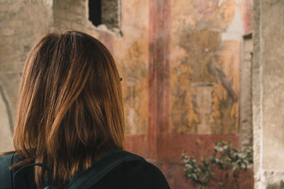 Rear view of woman standing against wall