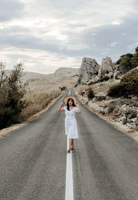 Portrait of woman standing on road against sky