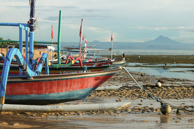 Fishing boats moored on beach against sky