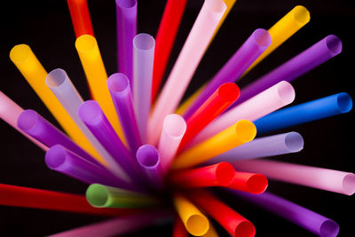 High angle view of multi colored drinking straws over black background