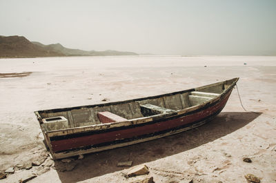 Abandoned boat moored on beach against sky