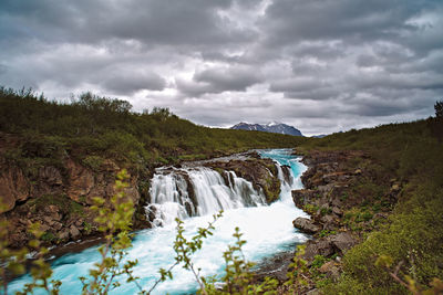 Scenic view of waterfall against sky