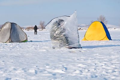 People on snow covered land against sky