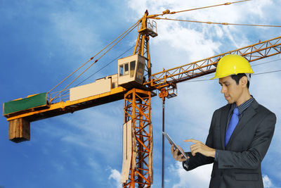 Low angle view of man standing at construction site against sky