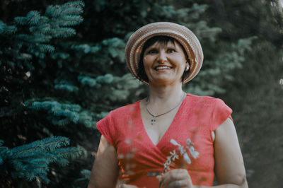 Portrait of happy mature woman holding flowers while standing at park