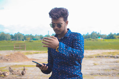 Young man using mobile phone on field