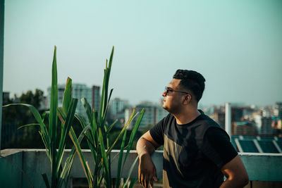 A boy looking away beside a sugar cane tree on the roof top