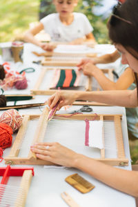 Girl weaving small rug with pattern at masterclass on weaving.