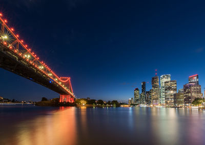 Illuminated bridge over river against sky at night