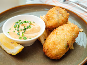 Close-up of croquette with cheese dip in plate